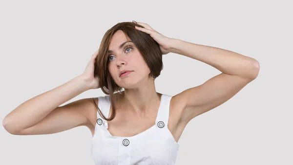 Woman in white dress playing with hair on gray background Stock Picture