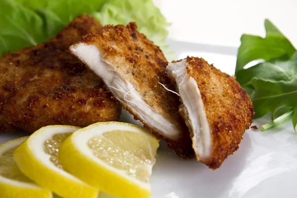 Paniertes Fleisch mit Zitrone und Salat lizenzfreie Stockbilder