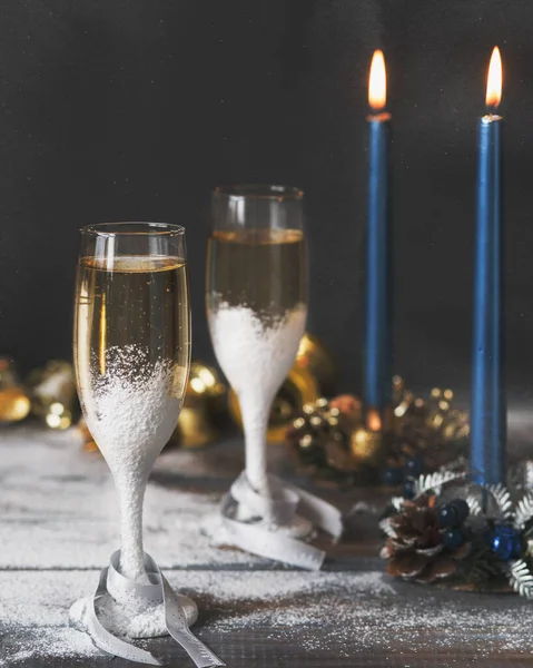 Two glasses of champagne and candles. A romantic date. New Year's atmosphere. Champagne and Christmas. New Year for lovers. Sparkling wine for winter holidays