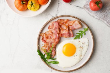  İngiliz kahvaltısı. Yumurta ve kızarmış pastırma. Domatesli bir fincan. Mermer bir masada kahvaltı servisi. Yağda yumurta..