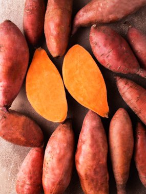 Kahverengi arka planda tatlı patates. Egzotik yemekler. Taze sebze mahsulü. Çiğ patates. Organik yiyecekler