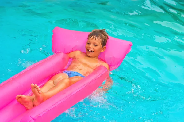 Der Junge liegt auf einer Matratze im Pool — Stockfoto