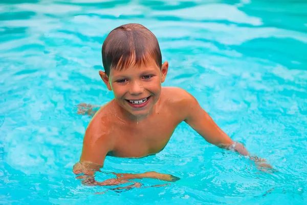 Sorridente ragazzo nuota in piscina durante le vacanze estive — Foto Stock