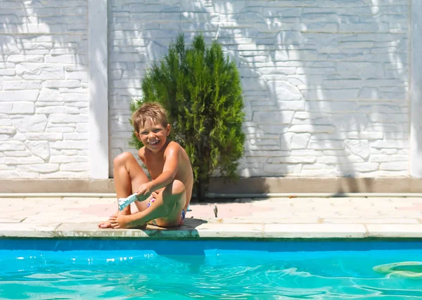 Smiling boy sits near the swimming pool — Stock Photo, Image