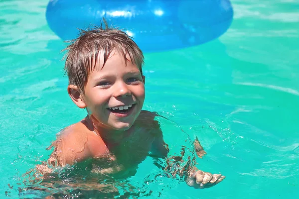 Garoto sorridente nada na piscina em férias de verão — Fotografia de Stock