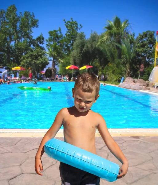 Серьезный ребенок стоит у бассейна на курорте — стоковое фото