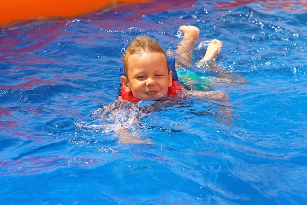 Criança entusiasmada em colete no parque aquático da piscina — Fotografia de Stock