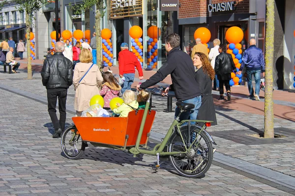 Les jeunes parents portent des enfants dans la poussette à vélo — Photo