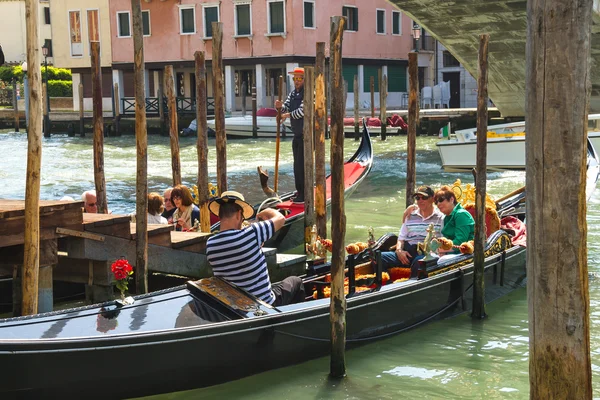 Gondolier photographs tourists sitting in a gondola, Venice, Ita — Stock Photo, Image