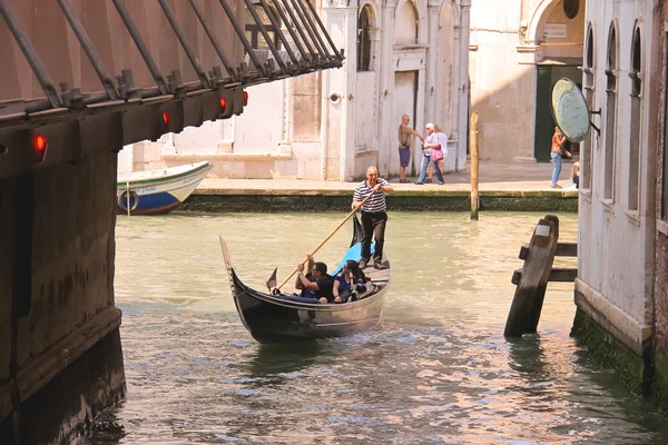 Gondolier sails with tourists sitting in a gondola down the narr — Stock Photo, Image