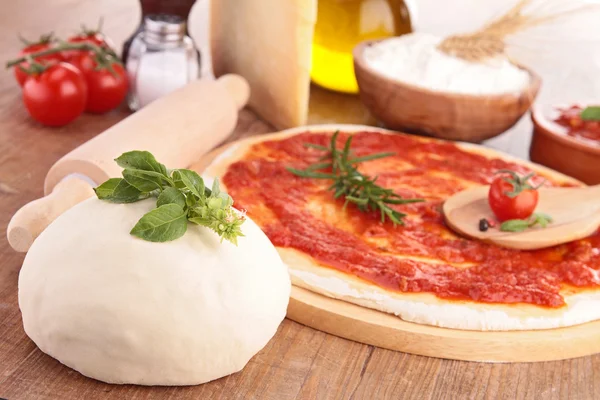 Pizza dough with tomato sauce and ingredients — Stock Photo, Image