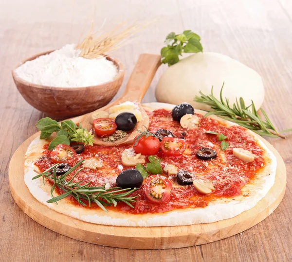 Pizza dough with tomato sauce and ingredients — Stock Photo, Image