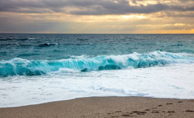 Turkuaz deniz ve gün batımında el salla
