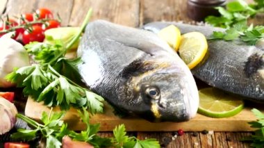 Maydanoz ve limonlu tahtanın üstünde çiğ yaldızlı balık.
