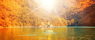 Çocuklar ayakta kürek çekerken eğleniyor.