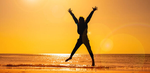silhouette of child jumping on the beach at sunset
