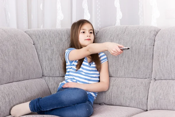 Sevimli küçük kız kanepede televizyon izlerken — Stok fotoğraf