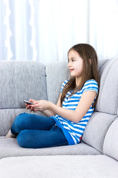 Söt liten flicka tittar tv soffan — Stockfoto