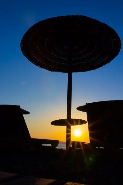 Beach umbrella on the beach at sunset — Stock Photo, Image