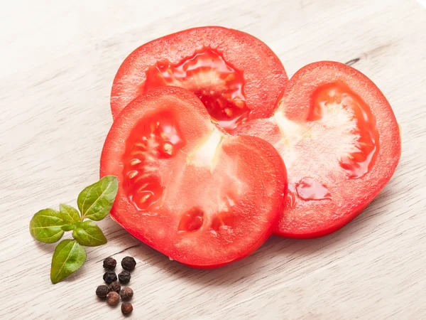 Tomates cherry frescos y maduros en una vieja tabla de cortar. Hojas de albahaca — Foto de Stock