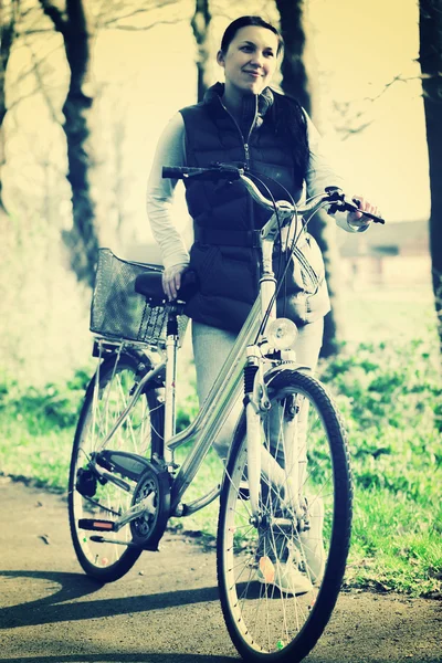 Beautiful smiling girl with a bicycle on the road — Stock Photo, Image