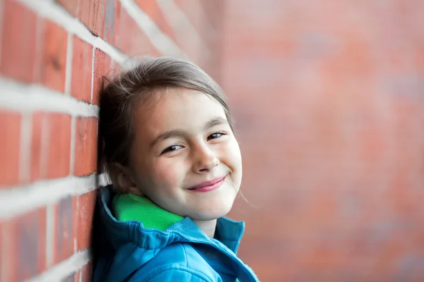 Porträt eines kleinen süßen Mädchens neben Ziegelmauer — Stockfoto