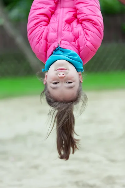 Ragazzina appesa a testa in giù su un parco giochi — Foto Stock