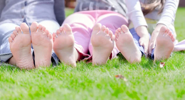 Group of happy children lying on green grass in park — Stock Photo, Image