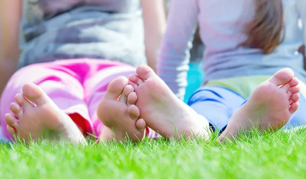 Group of happy children lying on green grass in park — Stock Photo, Image