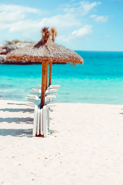 Stro parasols en ligbedden op het zandstrand. — Stockfoto