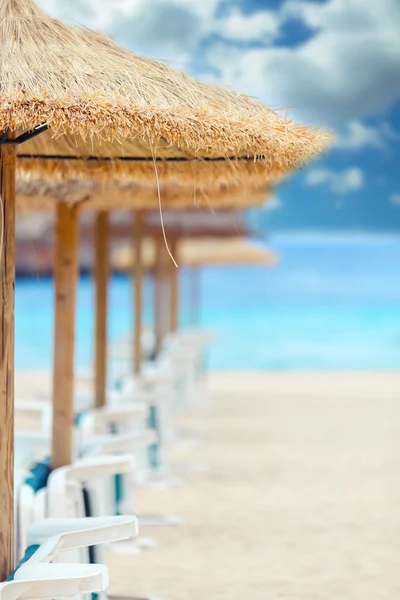 Straw parasols and beds on the sandy beach. — Stock Photo, Image