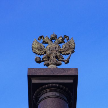Çift başlı bir kartalın tepesinde bir sütun. Kasvetli mavi gökyüzünün arka planına karşı Rusya 'nın arması.