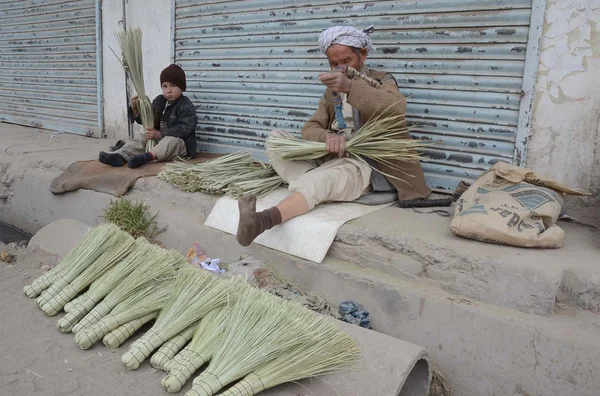 An aged man and a child prepare brooms to earn their livelihood for support their families — Stock Photo, Image