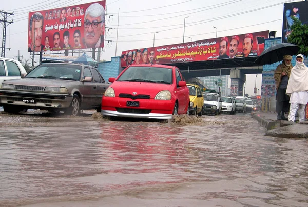 Commuters pass through stagnant rain water stand on the road at Sooriah Bridge, in Peshawar — Stock Photo, Image