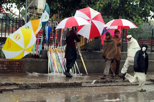 Man verkoopt paraplu's om te verdienen zijn levensonderhoud voor steun van zijn familie, tijdens stortbui van winterseizoen — Stockfoto