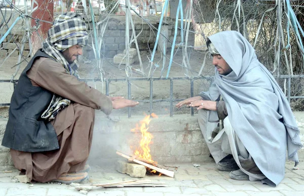 Residents of Quetta warm their hands on bone-fire to save themselves from cold waves during winter season, at footpath — Stock Photo, Image
