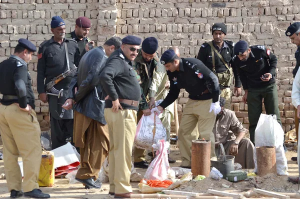 Polistjänsteman återvinns beslagtagna vapen under en räd på avgränsningen av greps anklagade, på quetta bypass — Stockfoto