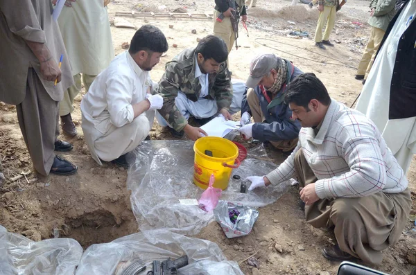 Сотрудники полиции проверяют изъятое оружие, найденное во время рейда на разграничение арестованных обвиняемых, на Кветте — стоковое фото