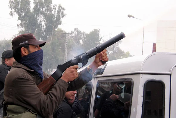 Polistjänsteman bränder tårgas shell att skingra demonstranter under protest demonstration av tehreek mutasireen — Stockfoto