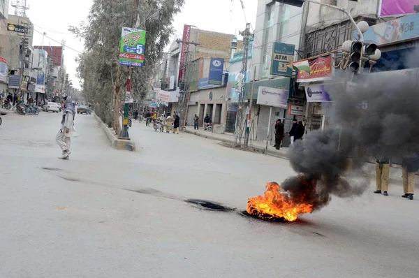 Angry protesters burnt tyres during shutter down strike called by Jamiat-e-Ulema-e-Islam and Baloch National Party (Awami) against governor rule in province Balochistan — Stock Photo, Image