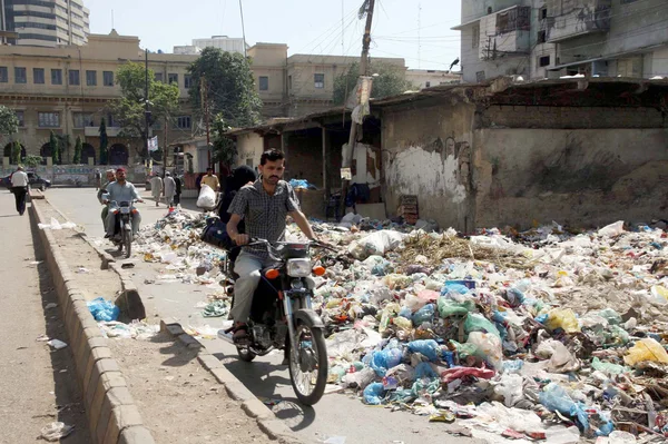 Los viajeros pasan cerca de un enorme montón de basura creando problemas para los ciudadanos. —  Fotos de Stock