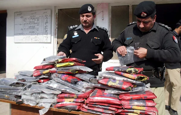 Funcionarios de la policía inspeccionan los paquetes recuperados de drogas (Charas), que fueron incautados durante la revisión a presión en la carretera Jamrud — Foto de Stock