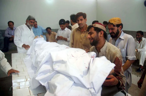 Gather near dead body of Awami National Party (ANP) candidate Sadiq Zaman Khattak, who assassinated along with his six years old son in Bilal Colony — Stock Photo, Image