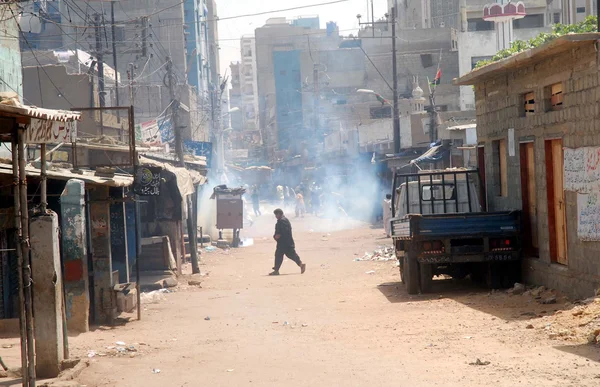 Funcionarios de la policía disparan proyectiles de gas lacrimógeno para dispersar a los manifestantes durante la manifestación de protesta de los residentes de Lyari contra el aumento de incidentes de asesinatos selectivos en la zona —  Fotos de Stock