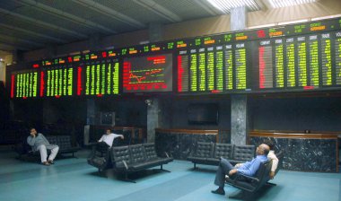 Pakistanlı tüccarlar Karaçi Borsası (Kse) tesislerinde elektronik bir ekran altında oturmak