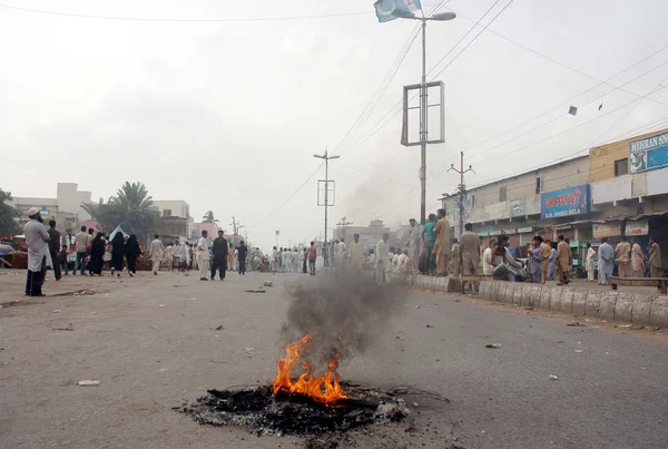 Residentes de Gulberg Town queman muebles de madera y neumáticos mientras protestan contra el siniestro de dos personas por un cable eléctrico que cae sobre ellos durante la manifestación —  Fotos de Stock