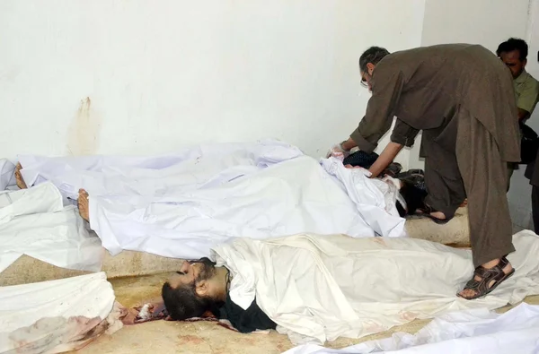 Οι άνθρωποι συλλέγουν κοντά σε νεκρά σώματα των θυμάτων, που σκοτώθηκαν σε μια ανταλλαγή πυρών με τις δυνάμεις ασφαλείας κατά τη λειτουργία — Φωτογραφία Αρχείου