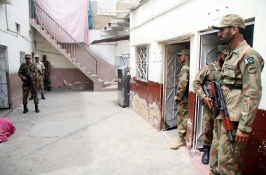 ps-95 orangi alan Karaçi'de seçim sırasında bir Yoklama İstasyonu uygunsuz olayları önlemek için uyarı güvenlik görevlileri standı