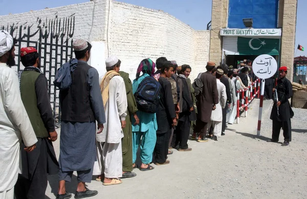 Des ressortissants afghans font la queue pour prouver leur identité alors que les forces de sécurité pakistanaises ont libéré 112 ressortissants afghans qui vivaient illégalement au Pakistan et ont été arrêtés par les forces de sécurité — Photo