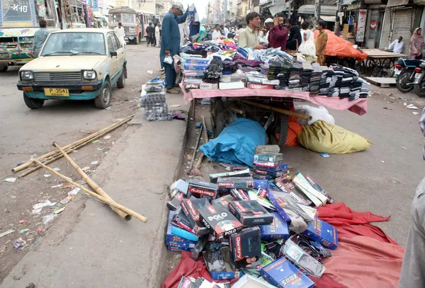 Торговцы заняты воспоминаниями о своих разбросанных вещах, которые полиция выбросила на дорогу во время акции против посягательства в Саддарском районе — стоковое фото
